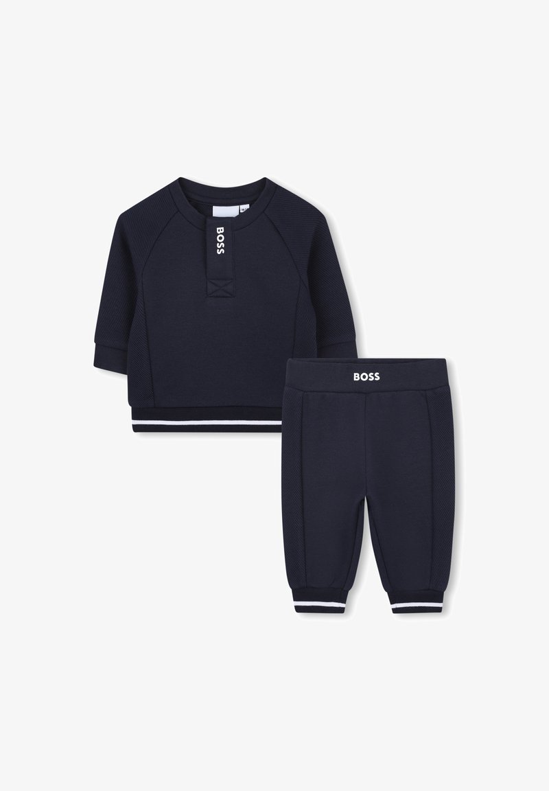 Granatowy zestaw dresowy dla dzieci składający się z krótkiego rękawka z teksturą ściśniętą oraz spodni z elastycznymi mankietami i białymi akcentami.