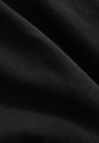 Melna auduma ar mīkstu, teksturētu virsmu, kas mazliet stiepjas un glīti krīt. Materiāls šķiet viegls un izturīgs.