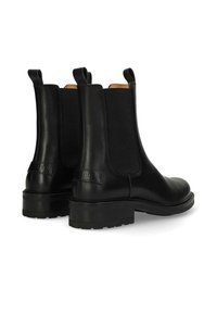 Botas Chelsea negras de cuero con paneles laterales elásticos, tiras de agarre y suela de goma. Presentan una textura suave y costuras reforzadas.