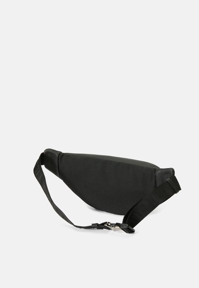 Riñonera negra hecha de tela suave con forma curva. Cuenta con una correa ajustable y un broche para un cierre seguro. Textura suave.