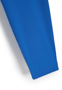 Niebieskie legginsy sportowe wykonane z gładkiego, elastycznego materiału o zwężanym kroju i płaskich szwach, bez widocznych wzorów czy elementów metalowych.