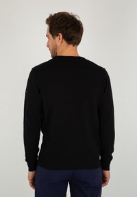 Maglione nero a maglia con scollatura rotonda, maniche lunghe e polsini a coste. Tessuto liscio, design semplice e senza motivi o decorazioni visibili.