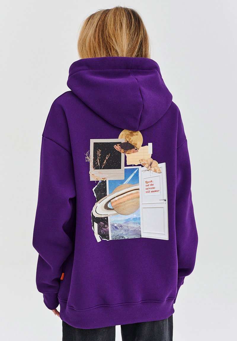 Fialová mikina s kapucí, na zadní straně s koláží, která obsahuje vesmírné obrázky, grafiku dveří a textové prvky. Vyrobena z měkké, strukturované látky.