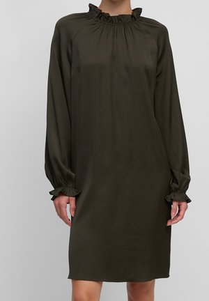 Langärmliges dunkelolivgrünes Kleid mit gerafftem hohem Kragen und gerafften Manschetten, getragen von einer Person vor einfarbigem Hintergrund.