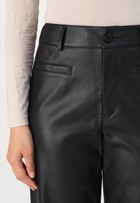 Zwarte leren broek met een gladde textuur, recht model, twee voorkruiszakken en een enkele knoopsluiting bij de taille.