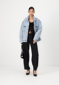 Svetlo modra denim jakna oversize, črn krajši zgornji del in ohlapne črne hlače. Dodatki vključujejo majhno črno torbico in pete.