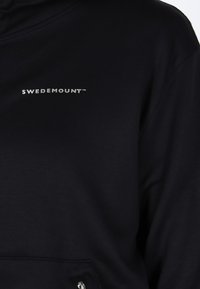 Sort sweatshirt med en lynlåslomme og sølvfarvet "SWEDEMOUNT™" logo på venstre brystområde, fremstillet af et glat stof.