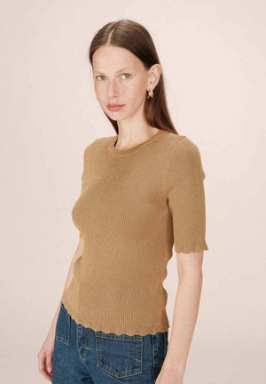 Top de punto acanalado marrón con mangas cortas y dobladillo en forma de ondas. Textura suave, diseño ajustado y escote redondo. Combinado con jeans azules.