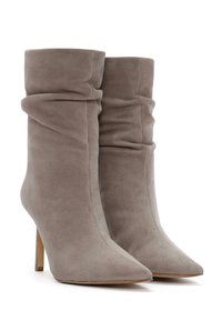 Botas de tobillo de ante topo con un diseño arrugado, punteras puntiagudas y tacones de aguja. La textura es suave y lisa, con un detalle mínimo.