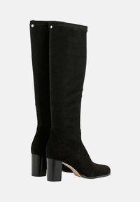 Bottes noires en daim montant jusqu'au genou avec un talon bloc, présentant une texture lisse et des accessoires décoratifs près du haut. Fermeture éclair sur le côté incluse.