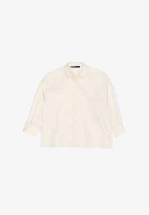 Jasna kremowa koszula z guzikiem, z kołnierzykiem, długimi rękawami i luźnym fasonem. Wykonana z bawełnianej tkaniny, charakteryzująca się gładką fakturą i podwiniętymi mankietami.
