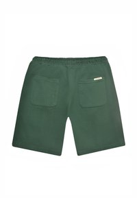 Shorts verts foncés avec taille élastique et deux poches carrées à l'arrière, dont une avec une petite étiquette de marque beige.