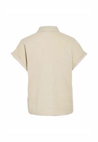 Camicia beige a maniche corte con una texture morbida, colletto a punta e una vestibilità rilassata. La parte posteriore presenta un design in tessuto leggero e discreto.