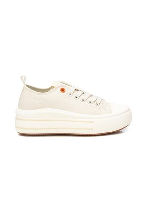 Zapatilla beige de lona de corte bajo con suela blanca gruesa, cordones blancos, ojal naranja cerca de la parte superior y lengüeta en el talón.