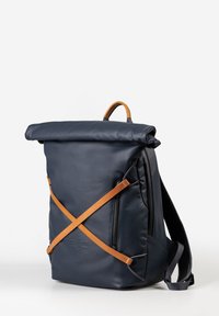 Zaino roll-top blu navy in pelle liscia, con spallacci in pelle marrone chiaro, una tasca laterale con zip e spallacci imbottiti.
