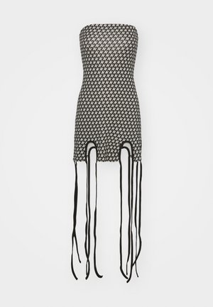 Strapless black and white mini dress with a geometric pattern, features cutouts at the hem, and long black ties hanging from the sides.