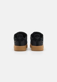 Mustat joka säärystimet, joissa on kumipohja, sileä tekstuuri, pyöreä muoto ja logovivahtelu kannassa.