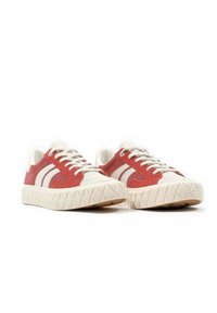 Sneaker rossi e bianchi realizzati in suede e tela, con una suola in gomma texture e un motivo geometrico, e una punta arrotondata.