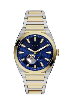 Orologio da polso Fossil con quadrante blu, cinturino metallico oro e argento, indici dorati, apertura sul movimento e piccolo quadrante dei secondi alle 5.