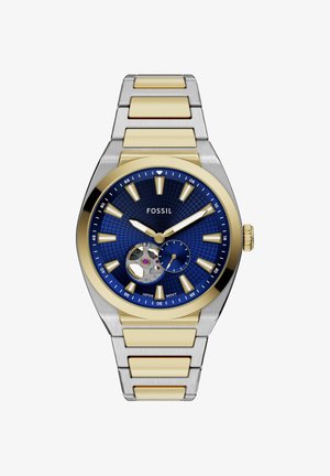 Orologio da polso Fossil con quadrante blu, cinturino metallico oro e argento, indici dorati, apertura sul movimento e piccolo quadrante dei secondi alle 5.