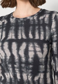 Camicia a maniche lunghe in cotone grigio scuro con un motivo astratto grigio chiaro, caratterizzata da un collo rotondo e una texture morbida.