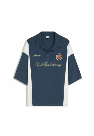 Mornarsko modra polo majica z belimi stranskimi ploščami. Ima vezeno logotip in besedilo v zlati barvi. Kratki rokavi in klasična zasnova ovratnika.