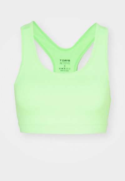 Neon green sports bra with a seamless design, wide straps, and a racerback style. Made of smooth, stretchy fabric. Label visible inside.