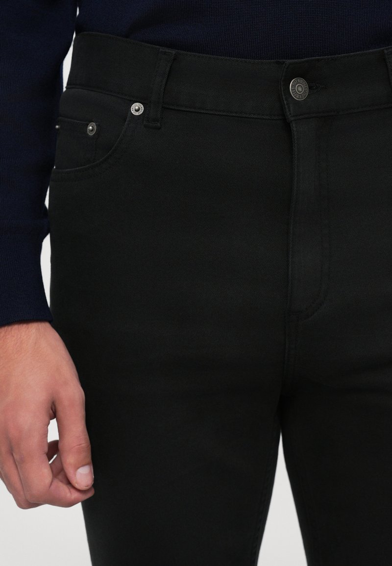 Zwarte denim jeans met een klassieke vijf-pocket ontwerp, subtiele stiksels en een sluiting met een knoop aan de voorkant; gladde textuur en slim fit.