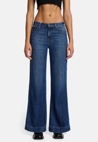 Weite, blaue Jeans aus Denim, mit einem klassischen Fünf-Taschen-Design und dezenten Abnutzungserscheinungen auf der Vorderseite, mit einem sauberen Saum und ohne Verzierung.