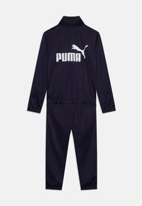 Mornarji modri trenirka iz gladkega materiala, s srajco na zadrgo in ovratnikom ter elastičnimi manšetami, in hlačami z elastičnim pasom. Bele Puma logotip na hrbtni strani.