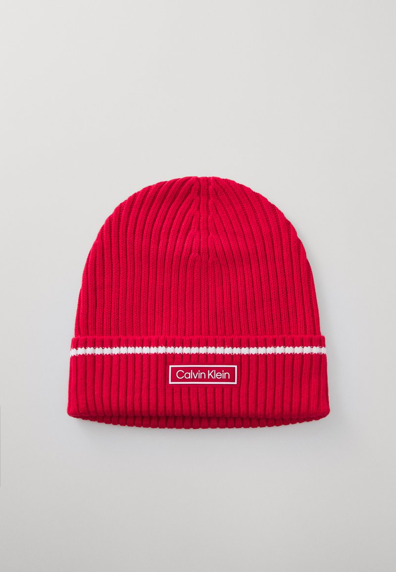 Rode gebreide beanie met geribbelde textuur, voorzien van een witte streep en een rechthoekig Calvin Klein-logo patch op de voorkant.