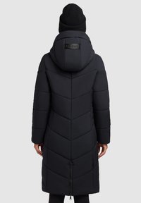 Sort dunjakke med en kilemønstret silhuet, hætte og lynlås. Har justerbar kant og en logoaccents på bagsiden af hætten.