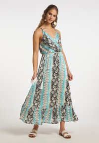 Maxi sukienka w czarno-biało-skalnym odcieniu teal; dekolt w serek, regulowane ramiączka, elastyczna talia oraz falbaniasty dół z akcentującymi frędzlami.