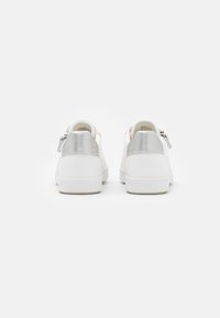 Sneakers bianchi in pelle con accenti in argento sul tallone e dettaglio con zip. Punta rotonda, suola piatta e design minimalista.