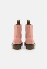 Pink leather ankle boots with a smooth finish, yellow stitching, and black platform soles; features pull tabs for easy wear.