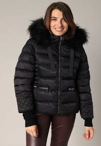 Doudoune noire avec une capuche en fausse fourrure, fermeture éclair à l'avant et poches, panneaux texturés et poignets élastiqués. Fabriquée en tissu durable et brillant.