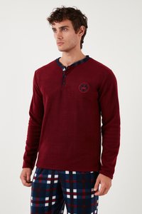 Bordová košeľa s dlhým rukávom a gombíkovým henley golierom, s nášivkou na hrudi a kockovaným akcentom na golieri. Skombinovaná s vzorovanými pyžamovými nohavicami.