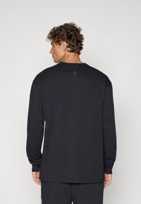 Sort langærmet t-shirt lavet af blødt stof, med ribbet rund hals og et lille logo-tag på ryggen. Skåret i en afslappet pasform.
