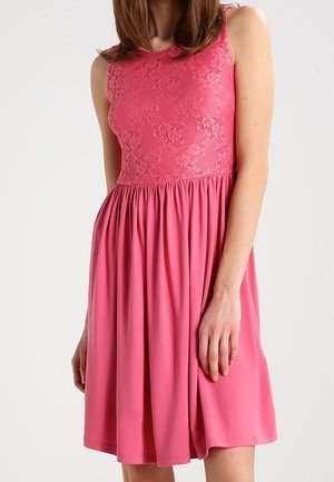 Robe rose avec un corsage en dentelle, un design sans manches et une jupe fluide. Le tissu est lisse avec une texture douce et se rassemble à la taille.