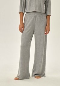 Szare, luźne dresowe spodnie z miękkiego, strukturalnego materiału z elastyczną talią i szerokimi nogawkami, w zestawieniu z topem o krótkim kroju.