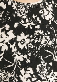 Textilie s květinovým vzorem v černobílé barvě s jemnou texturou; obsahuje abstraktní květiny a listy, navržena s ribbovaným povrchem.