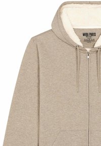 Hoodie zippé en beige clair avec une douce doublure en polaire blanche. Doté de cordons de serrage, de poches avant et d'un design décontracté.