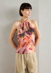 Haltertop aus leichtem Batikstoff in den Farben Pink, Orange und Purpur. Geschmeidige Textur, lässige Passform, kombiniert mit beigen Hosen.