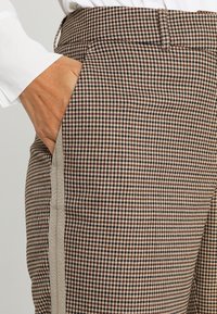 Bruna och beige rutiga byxor med slim fit, som har sidofickor och en kontrasterande beige rand längs sömmen.