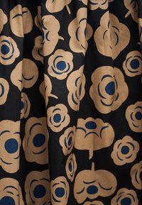 Μαύρο ύφασμα με ένα μπεζ και μπλε στυλιζαρισμένο ανθηρό μοτίβο που περιλαμβάνει διάφορα σχήματα λουλουδιών και στρογγυλεμένα πέταλα.