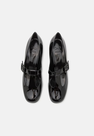 Zapatos de charol negro con un diseño de punta redonda, que cuentan con una correa al estilo Mary Jane y un detalle de hebilla lateral. Textura suave y brillante.