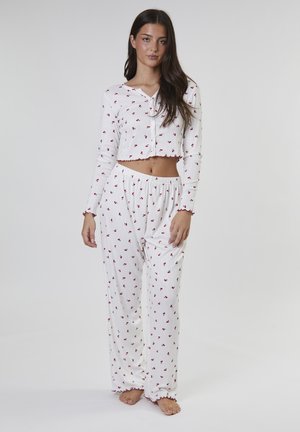 Wit pyjamaset bestaande uit een kort, knoopjes-topje met een rood kersenpatroon en een lange broek met een vergelijkbaar ontwerp en elastische tailleband.