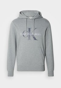 Sudadera de color gris claro de Calvin Klein con bolsillo frontal, capucha con cordón y logo "CK Calvin Klein Jeans" en el pecho.