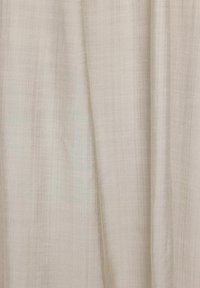 Ljusbeige gardin tillverkad av ett texturerat, vävt tyg med en något genomskinlig utseende, som har vertikala, subtila linjer genom hela.