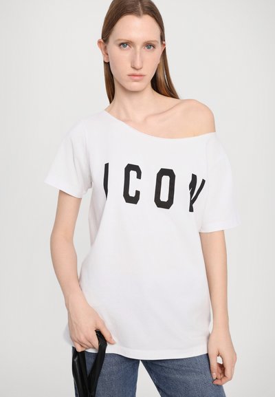 T-shirt blanche avec un design dénudé d'épaule, arborant des lettres "ICON" noires en gras. Tissu doux, manches courtes et coupe décontractée.